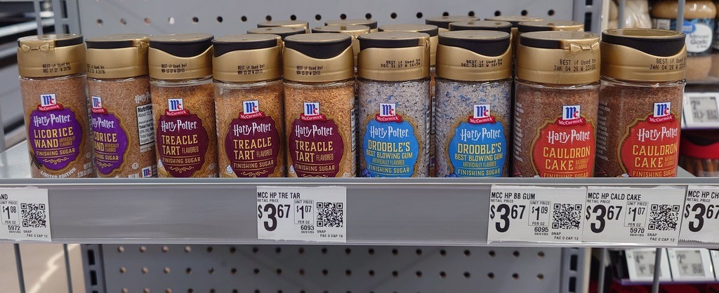 Mehrere Gewürzbehälter der Marke McCormick mit Harry-Potter-Etiketten stehen im Supermarktregal. Sichtbar sind Sorten wie Treacle Tart und Cauldron Cake